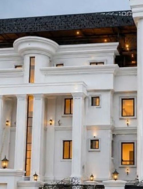 Front elevation of the building in Ogba-Ikeja: a white columned facade with warm-lit windows